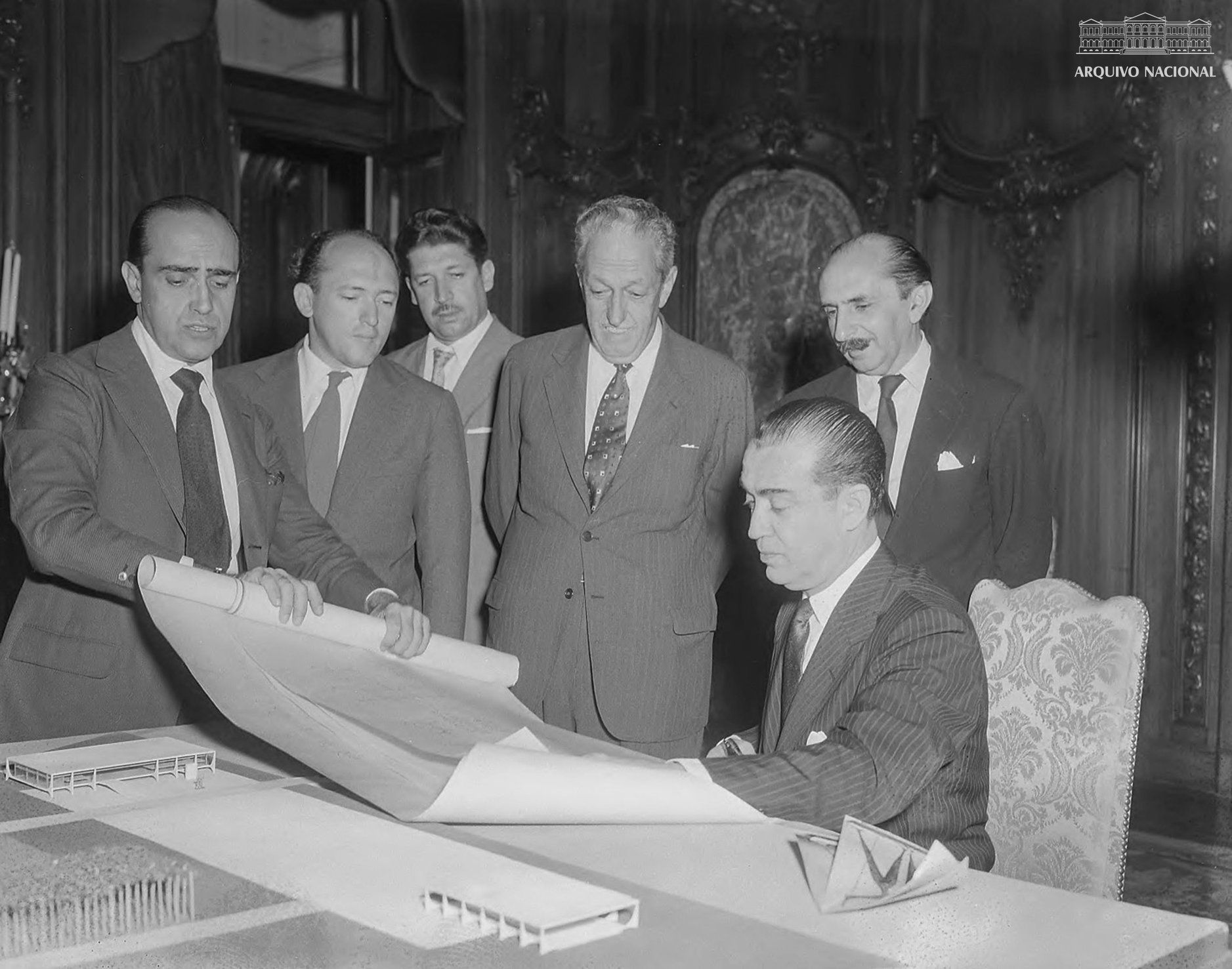 O presidente Juscelino Kubitschek, junto com os arquitetos Oscar Niemeyer e Lucio Costa, envolvidos na concepção da cidade modernista e futura capital do Brasil.